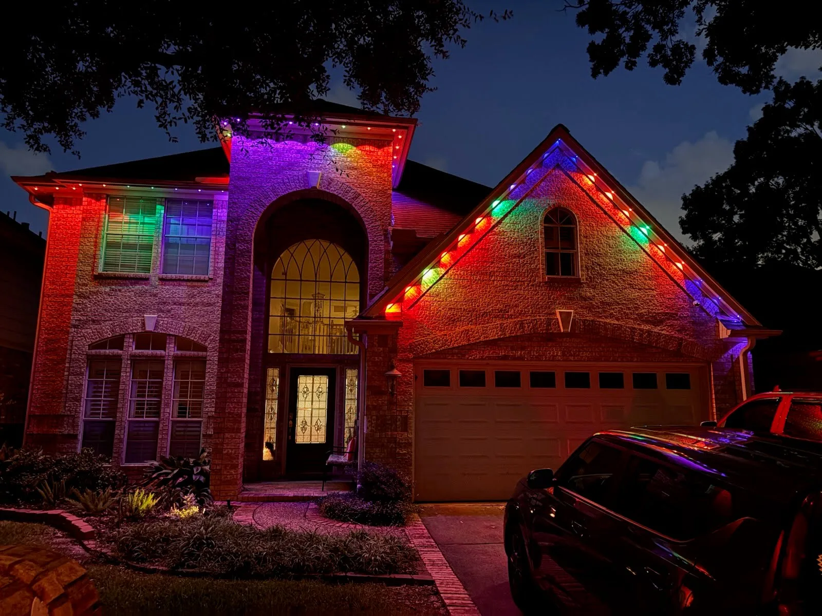 Real Skyclear install — brick home with permanent roofline lighting in full multicolor at night
